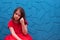 A young girl in a red dress is sitting on the floor and she is very upset