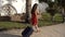 Young girl in red dress traveling on street with suitcase