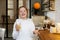 Young girl with red hair, teenager, in a modern kitchen playing with an orange, drinking orange juice, happy