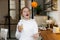 Young girl with red hair, teenager, in a modern kitchen playing with an orange, drinking orange juice, happy