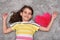 Young girl with red plush heart lying on the carpet