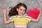 Young girl with red plush heart lying on the carpet