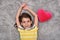 Young girl with red plush heart lying on the carpet