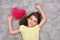 Young girl with red plush heart lying on the carpet