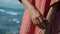 A young girl in a red shirt with white stripes stands in nature with the sea and clouds on the back background