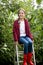 Young girl in red wellington boots sitting on stepladder at gar