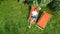 Young girl relaxes in summer garden in sunbed deckchair on grass, woman reading book outdoors in green park on weekend