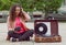 Young girl relaxing in city park, and listening music with headphones and a portable stereo vinyl record system