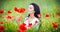 Young girl relaxing in green poppies field. Portrait of beautiful brunette woman posing in a field full of poppies