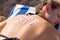 Young girl is relaxing on the sunbed at the beach and has spf word on her back made of sun cream. Sun protection factor concept