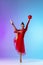 Young girl, rhythmic gymnast in red dress with ball standing isolated on purple blue gradient neon background.
