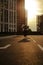 Young girl riding longboard on the boardwalk, silhouette on sunset