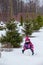 Young girl rolling snowball for a snowman at winter