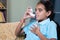 Young girl rubbing her chest after taking asthmatic inhaler at home - Concept of Teenager kids healthcare and medical