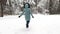 Young girl running on trail through snowy forest. Happy woman jogging on path at woodland. Cheerful lady having fun and