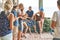 Young girl`s first attempt at playing the guitar in company of friends while hanging out on vacation at an old wooden