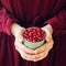 Young girl`s hands holding a cup full of raw organic fresh cowberry or lingonberry