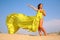 Young girl on sand in yellow fabric shawl