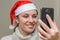 Young girl in santa claus hat talking on video communication with her friend