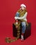 Young girl in a Santa hat is sitting on a black cube. photo session in the Studio on a red background