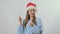 Young girl in santa`s hat shows a credit card with thumb up at white background