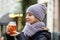 A young girl in a scarf and hat is drinking a hot drink on the street. Walk through the Christmas streets, hot tea in your hands.