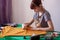 A young girl seamstress cuts out a mask pattern with scissors.