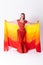 Young girl with shawl and in red dress performs oriental dance on white background