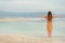 Young girl with shining blonde hair goes to seaside, Dead Sea beach. Banner. Travel, summer vacation, holiday, freedom concept.