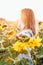 A young girl in a shirt stands in sunflowers