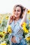 A young girl in a shirt stands in sunflowers