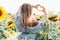 A young girl in a shirt stands in sunflowers