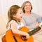 Young girl sing play guitar to grandmother