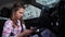 A young girl sits behind the wheel and reads something focused on the phone. 4K Slow Mo