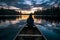 A young girl sits on a canoe at dusk