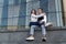 Young girl sits on her boyfriend`s lap. Stylish young couple hugs and resting in the city. Bottom view