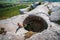 Young girl sits with panoramic view of huge hole in ground among green field and mountain on sunny summer day in Crimea.