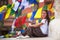 Young girl sitting on Buddhist stupa, prayer flags flying in the background. Travel.