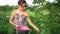 Young girl sitting on chair, collecting berries in garden.