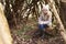 Young girl sitting in a forest shelter made of tree branches