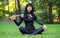 Young girl sitting on the grass and holding samurai sword.