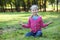 Young girl sitting in lotos pose on summer lawn