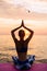 Young girl sitting in lotus position on sunrise, near the sea