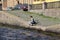 Young girl sitting and reading a book on a rocky river Bank