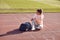 A young girl is sitting on a track and listening to the music at the stadium while preparing for a training. Sport, athletics,
