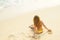Young girl sitting on tropical beach turned wistfully looking at the sky. Summer woman background of the ocean and sand. Top view.