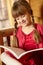 Young Girl Sitting On Wooden Seat Reading Book