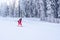 Young girl skiing downhill fast near the fir trees at a mountain resort