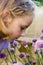 Young girl smelling purple flowers.