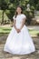 Young girl smiling with crossed hands, ready to take her first communion. White dress of religious communion